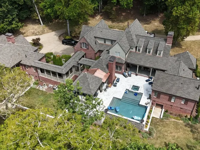 Drone view of a large brick estate with a new dark architectural shingle roof and pool, Brentwood TN