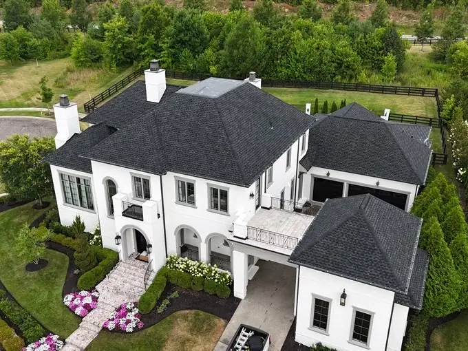 White brick two-story home with a freshly installed charcoal shingle roof in Franklin, TN