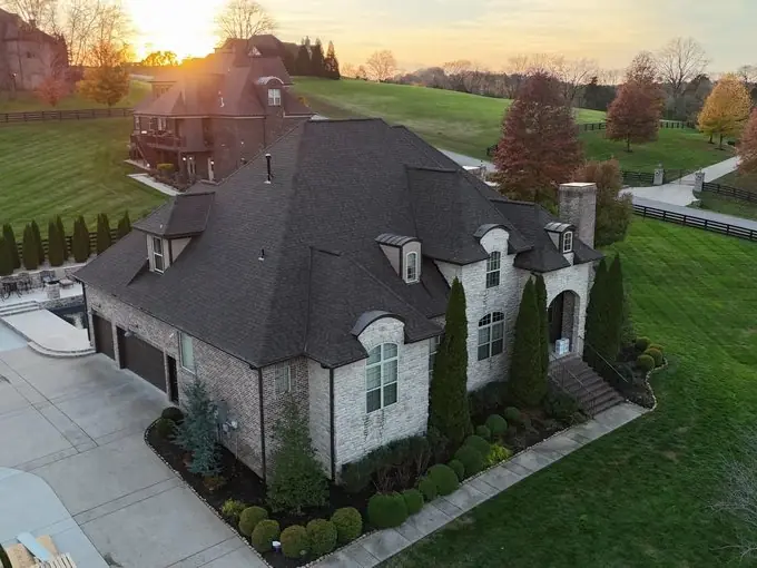 Sunset drone photo of a completed roof replacement on a stone and stucco home in Franklin, TN