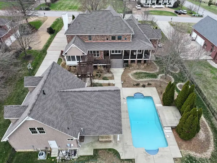 Aerial view of a re-roofed home with a pool and mature landscaping