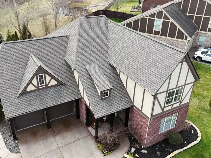 Tudor-style brick home with a completed architectural shingle roof