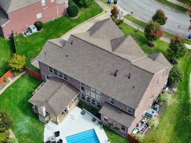Aerial view of a brick home with a new roof and backyard pool