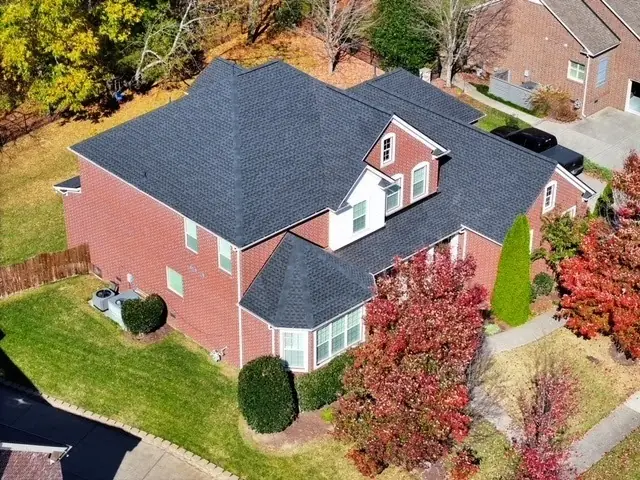 Brick home with new charcoal roofing and fall foliage