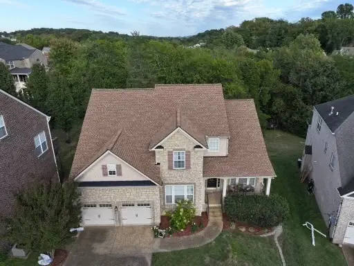 Two-story home with a weathered-wood shingle roof replacement by Three Stone