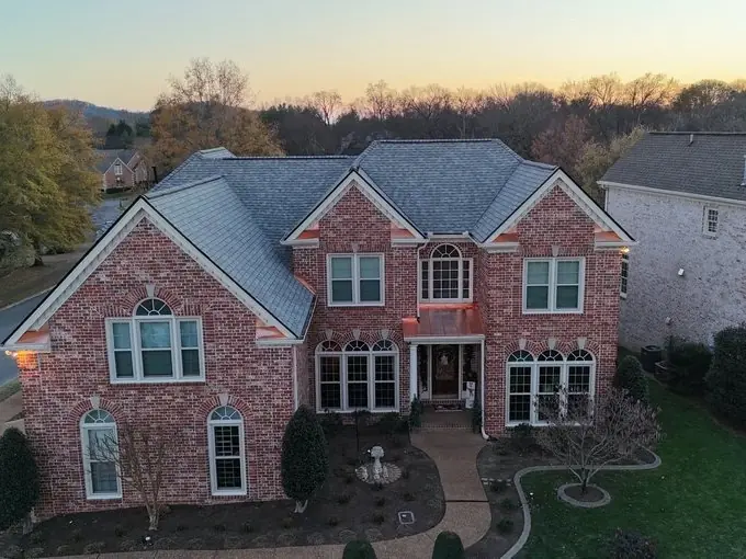 Brick two-story home at dusk with a completed roof replacement in Franklin, TN