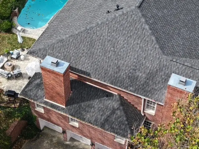 Close aerial of a new charcoal shingle roof and brick chimney flashing
