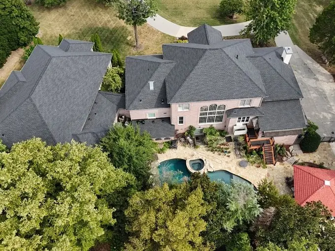 Aerial of a stone home with a new roof, pool and outdoor living area
