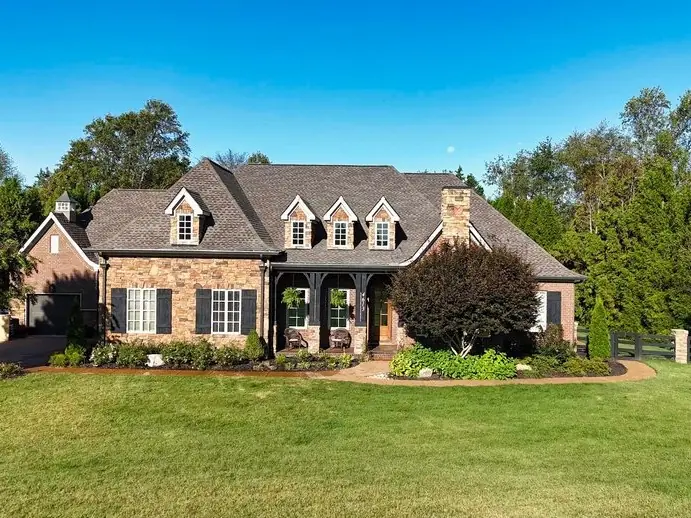 Stone-front home with a completed architectural shingle roof and manicured lawn
